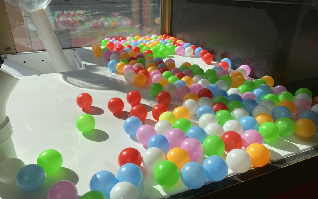 A white claw machine base full of multi-colored ping pong balls.