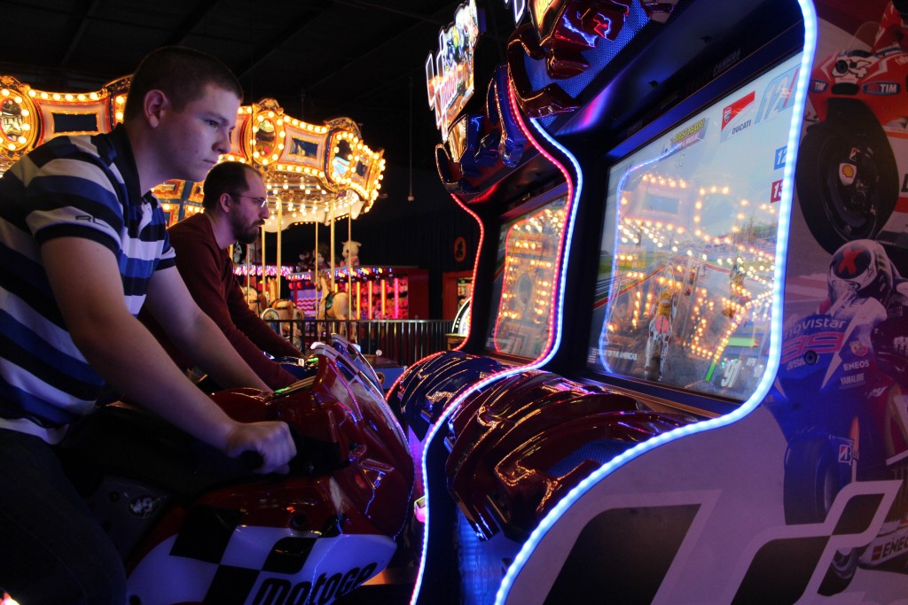 A young man on the back of a bike in an arcade machine.